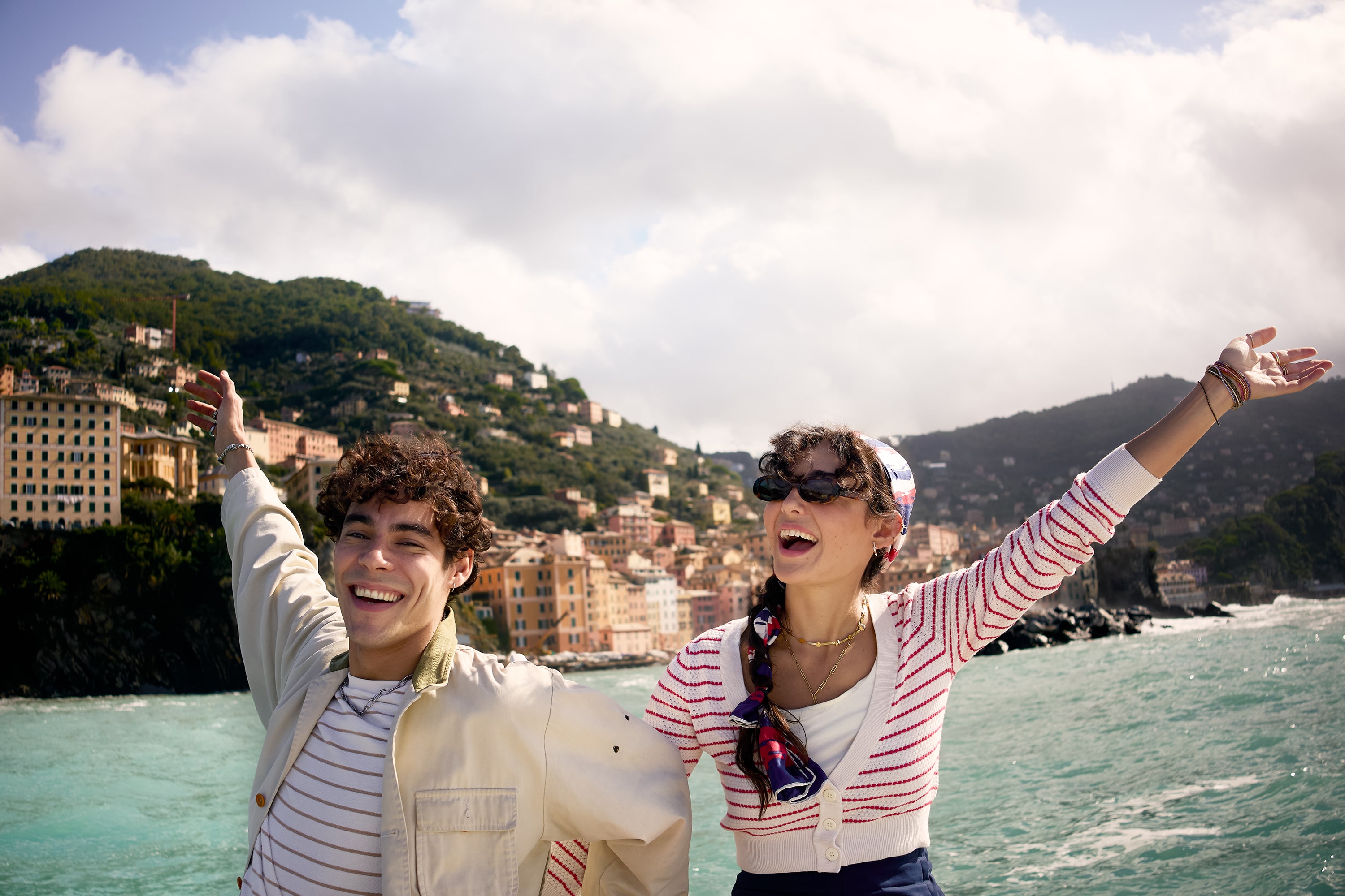 Two People Posing in Front of a City Near the Water